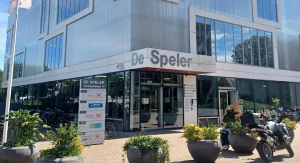 Ingang van het gebouw De Speler. op de voorgrond plantenbakken en een motorfiets